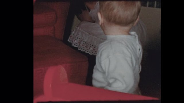 1953 Baby boy climbs on chair with sisters watching