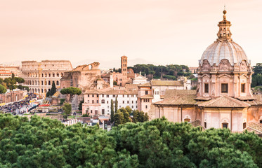 Panoramic view of the Colosseum and rooftops at sunset, Rome, Italy.