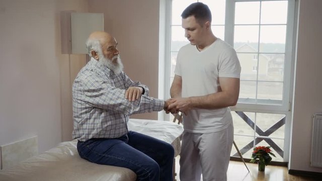 Professional masseur examines pain in wrist of an old patient