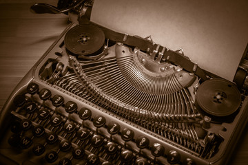 Typewriter ready for use with blank paper installed macro black and white background. Top view. Sepia tone