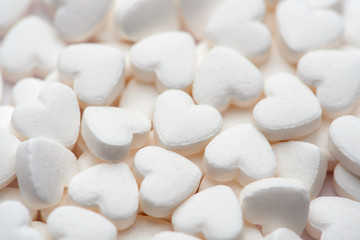 Fototapeta na wymiar Pharmacy theme. White pills in the form of hearts on white background.