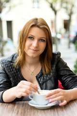 Attractive young woman drinking coffee latte outside in a bar terrace