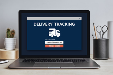 Delivery tracking concept on laptop screen on modern desk. All screen content is designed by me. Front view.