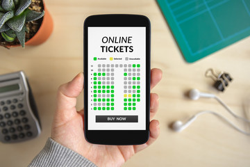 Hand holding smart phone with online tickets concept on screen. All screen content is designed by me. Flat lay