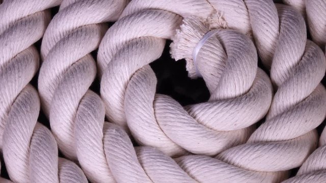 Amazing white cable in flat roll close up, rotating clockwise on black backdrop. Great equipment macro background with natural detailed texture in 4k, 3840x2160, clip. 
