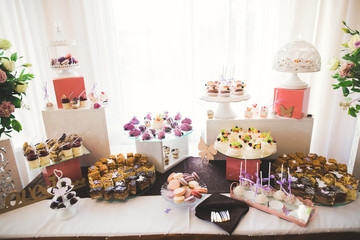 Delicious and tasty dessert table with cupcakes shots at reception closeup