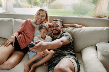 Relaxed family watching tv together - Powered by Adobe