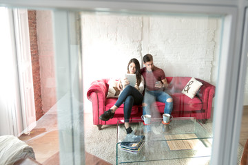 Fototapeta na wymiar Happy young couple relaxed at home with a tablet