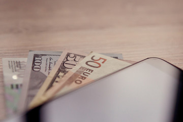 banknotes of different countries lying under the phone