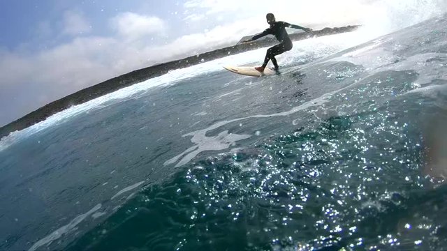 SLOW MOTION UNDERWATER: Experienced surfer guy carving a big blue wave before sundown. Fit male surfboarder rides a fun wave in cloudy weather before the sunset. Surfer catches last waves of the day.