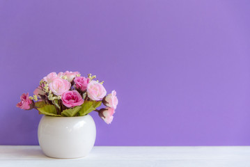 Purple wall with flowers on shelf white wood, copy space for text. Still life Concept