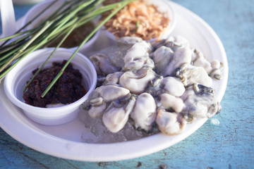 Fresh oyster on a plate with vegetable and seafood sauce