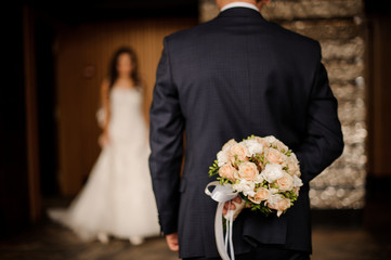 groom keeping behind a bouquet of roses waiting for bride - obrazy, fototapety, plakaty