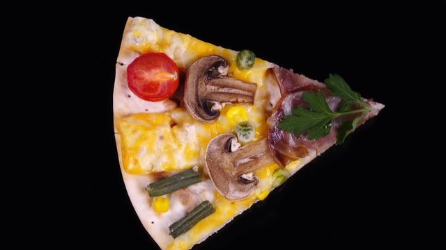 Amazing top view of pizza portion with ham, mushroom, cheese, green beans and tomatoes close up, rotating clockwise on black background. Vibrant natural texture with excellent details in UHD 4k clip.
