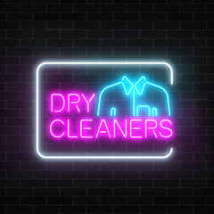 Neon dry cleaners glowing sign with shirt in rectangle frame on a dark brick wall background.