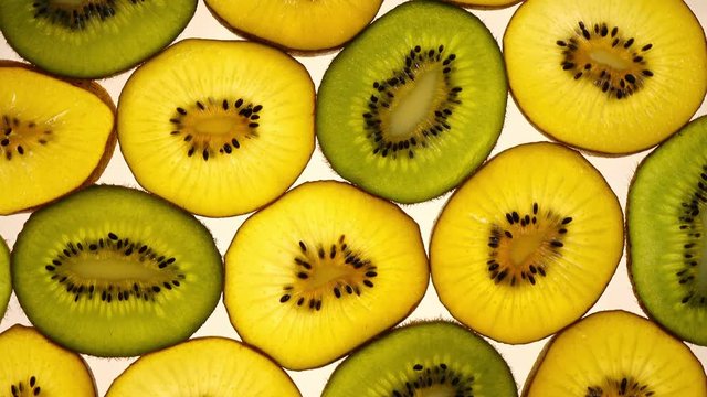 Excellent top view of sliced green and golden kiwi fruit in flat lay close up, rotating clockwise. Amazing natural background with vibrant texture and backlight in UHD 4k clip. Beautiful dessert.