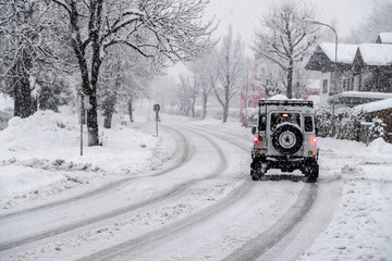Verschneite Straße und Auto, Wintereinbruch