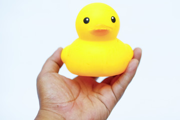 Hand Holding Yellow Rubber Duck Toy Over White Background