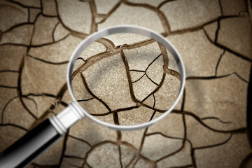 Cracked ground seen through a magnifying glass - The effects of drought - Concept image