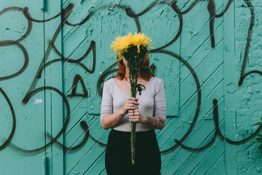 woman holding a yellow flower bouquet hiding her face