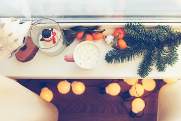 Christmas story, a window of a country house, a garland, a mug with marshmallow