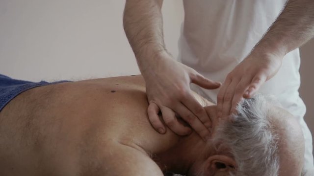 Masseur massages nape of old man