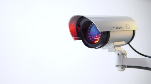 The surveillance camera with flashing red light on white background. Close up