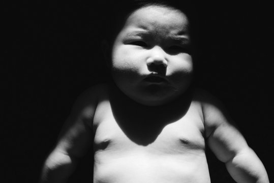 Black and white portrait of chubby baby lying in sunlight
