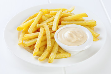 A plate of French Fries with Mayonnaise ina little bowl.