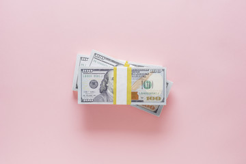 Overhead view of stack of 100 dollar bills on pink background