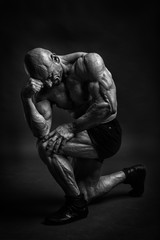 Professijnal bodybuilder and fitnes model posing in studio like a philosopher. Black and white low...