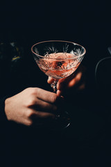 hand with alcohol cocktail making toast isolated on a black background