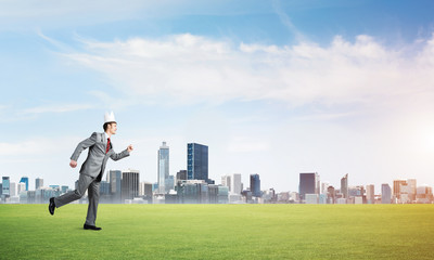 Fototapeta na wymiar King businessman in elegant suit running on green grass and modern cityscape at background