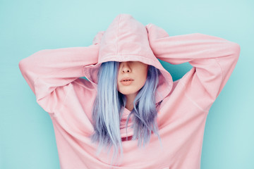 Young woman with blue dyed hair in pink hoodie
