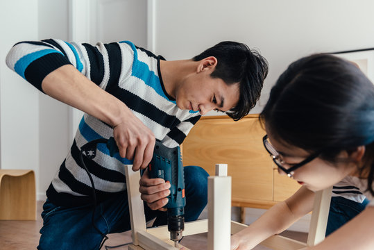 Young couple assembling flat-pack furniture