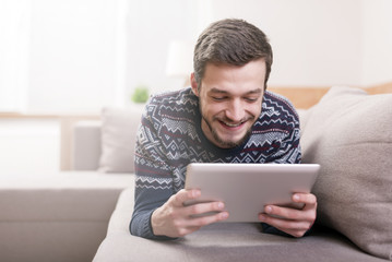 Young smiling man with a tablet computer in hand at home.