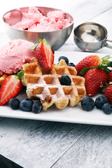 Plate of belgian waffles with strawberry ice cream, and fresh strawberries