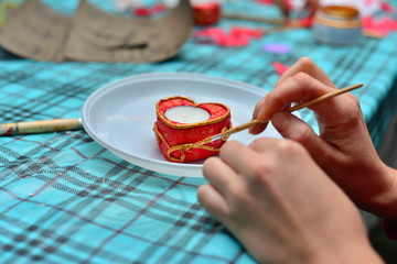Woman decorating heart-shaped articles for Valentine's day. Woman decorating heart shaped cookies with pink cream. Cookies for Valentine's Day