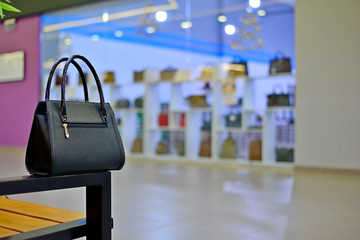 black bag in the shop window in the mall. Luxury and fashionable brand window display. New collection of casual clothings and bags.