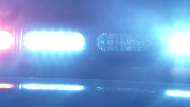 Close up on bright red and blue flashing lights from emergency vehicle with smoke blowing by.