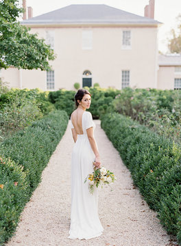 Beautiful young bride standing in garden holding a flower bouquet