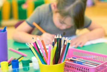 A cute Caucasian child draws at a table in a kindergarten.