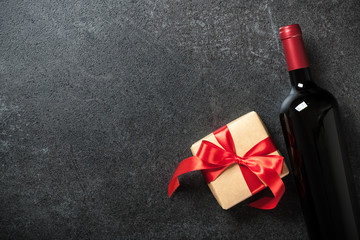 Red wine bottle and gift box on black background