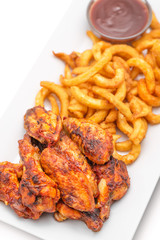 grilled chicken wings with french fries an tomato sauce on white plate
