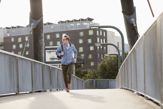 Attractive blonde man running with bag on his shoulder