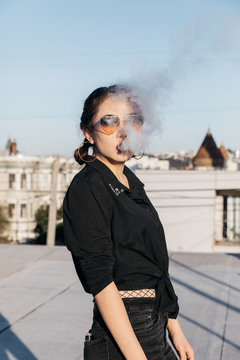young woman smoking with cloud puff smoke in front of face