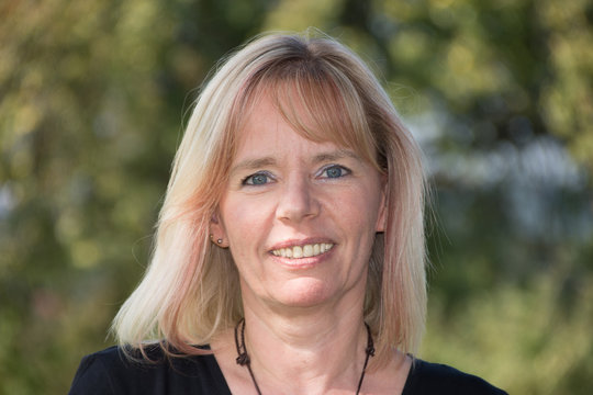 Portr&auml;t einer Blonde Frau im Sommer vor gr&uuml;nem Hintergrund