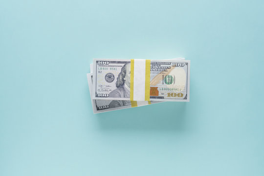 Overhead view of stack of 100 dollar bills on blue background