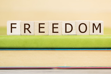 Freedom word built with letter cubes on green book
