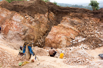 Lugazi, Uganda. June 18 2017. A Ugandan woman and boy breaking rocks into small slabs for their...